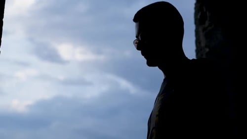 Silhouette of a Man Praying on a Rosary Against a Blue Sky