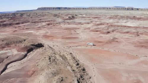 A smooth aerial shot of an RV driving through the Utah desert on an American roadtrip.