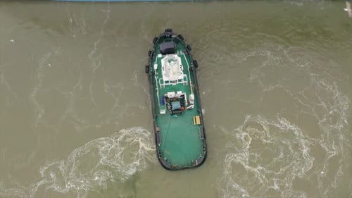 Tug boat assisting cruise ship arrival to port. Bottom sediment mixed by vessel propulsion. High alt