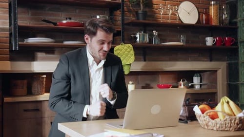 Man Dancing in Kitchen While Working on Laptop
