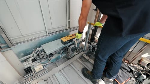 Young man mechanic engineer working doing maintenance on elevator lift at construction site slow mot