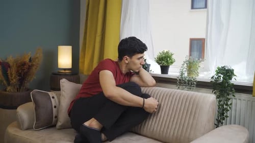 Depressed man. The man is watching out the window.