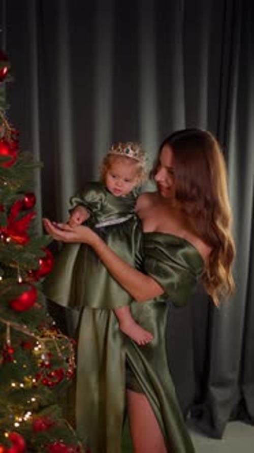 Mother Holding Little Daughter While Looking at Christmas Decorations Together Concept of Loving