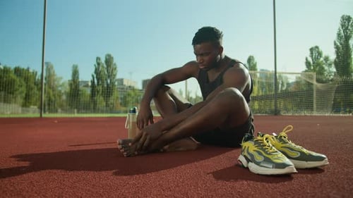Man Ankle Stretch on Athletic Court Outdoors