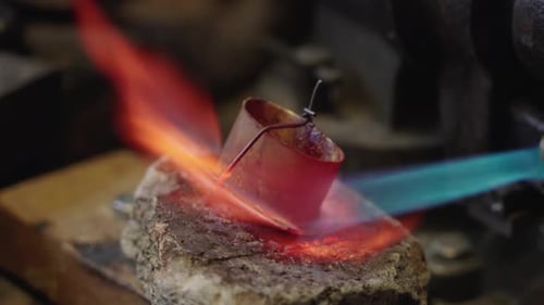 Artesão soldando a ponta da bainha na oficina