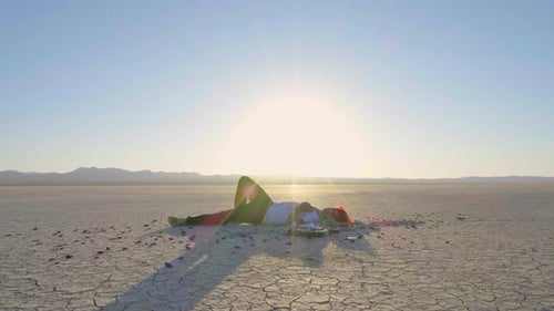 Person Lying on Cracked Earth in Desert Landscape