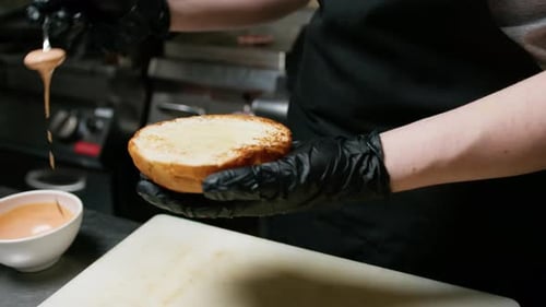 Chef Adding Sauce to Delicious Burger Bun
