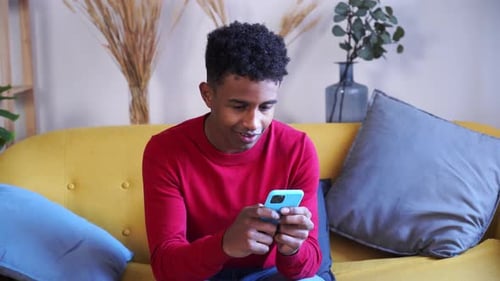 Young Man Using Phone Sitting on Couch