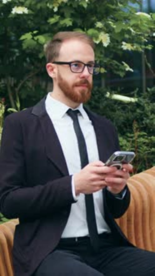 Young Businessman Analyze Data While Sitting on Bench in Business District Handsome Male Checking