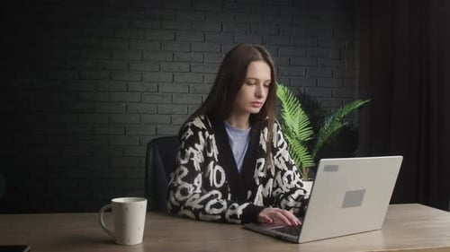 Serious Woman Freelancer is Typing at Her Computer While Sitting in the Studio Remote Work at the