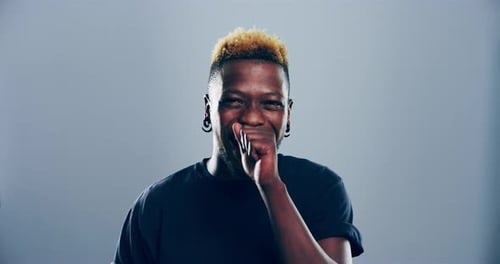 4k video footage of a young man laughing against a grey studio background