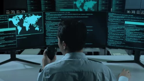 Asiatischer Mann trinkt Kaffee und benutzt Computer, um Code mit mehreren Bildschirmen im Büro zu schreiben