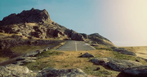 Winding Road Leads Through Rocky Mountains Under Bright Blue Sky