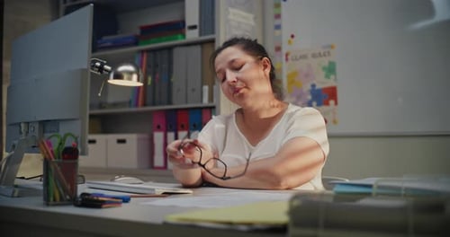 Tired Female Teacher Sitting at Computer in Empty Classroom Feeling Stress Burnout