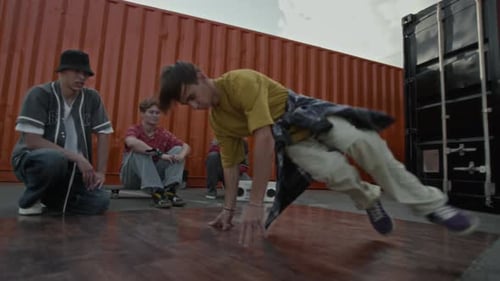 Un B-Boy de la génération Z se tient debout tout en faisant une pause entre amis à l'extérieur