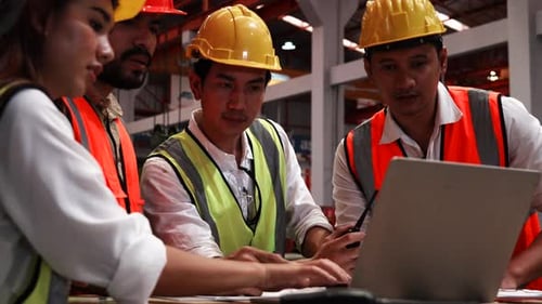Four heavy industrial engineers stand together in a steel factory.