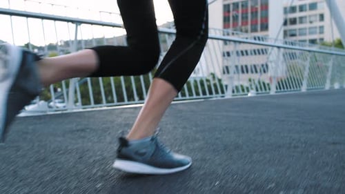 Fitness woman feet wearing running shoes and running fast up stairs on an urban city bridge