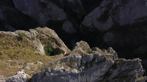 Flying through vertical limestone walls in a deep gorge, canyon, rock climbing aerial