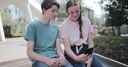 Teenagers socialising outdoors in city looking at smartphone