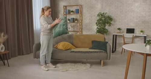 Woman Adding Yellow Pillow to Cozy Living Room Sofa