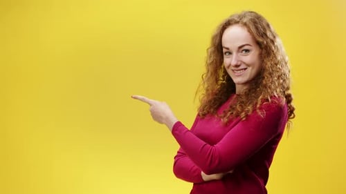 Smiling Woman Pointing to Side on Yellow Background