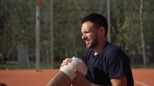 Portrait of Caucasian Man with Knee Injury Suffering From Pain on Sports Field