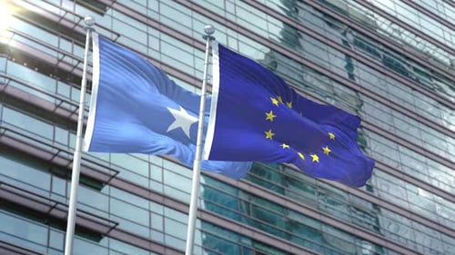 Somalia and European Union Flags Waving with Modern Building Background