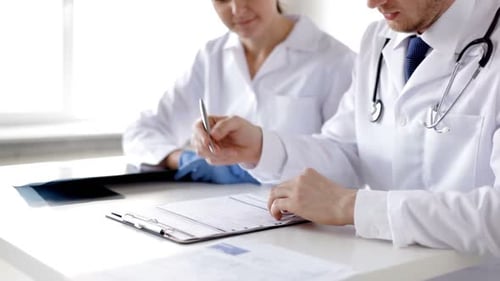 Two young doctors examining x-ray prints and medical reports at the hospital