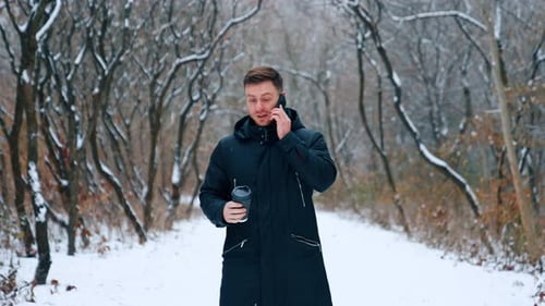 Man Talking on Phone in Snowy Winter Forest