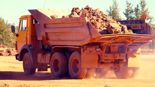 Truck Driving on Dirt Road Transporting Rocks