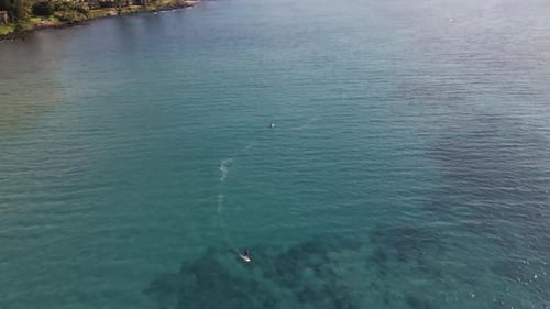 Surfer on electric surfboard speeding on wide azure ocean water, Maui, Hawaii
