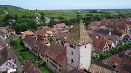 A smooth drone shot revolving around the clock tower while revealing the grassland, some crops and t
