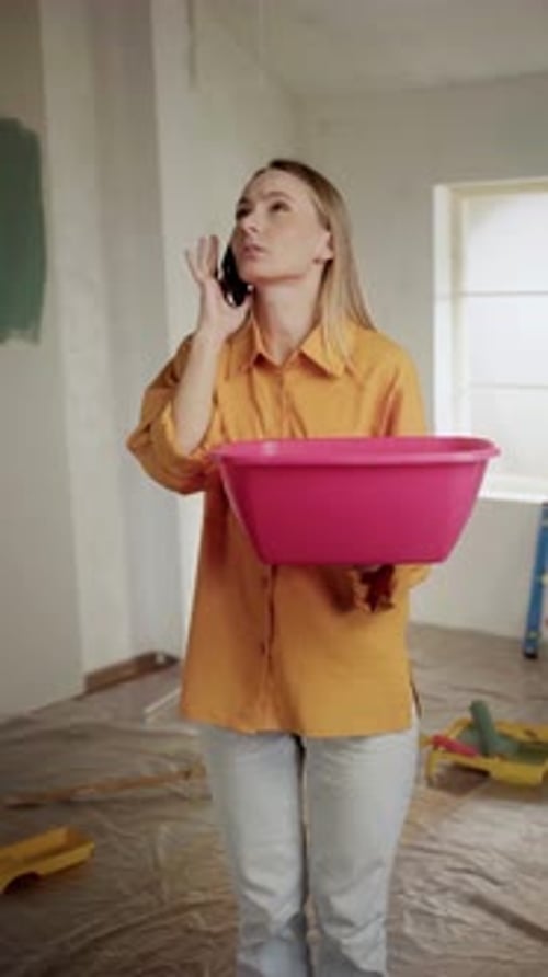 Woman Calling Insurance Company for Leaking Ceiling During Home Renovation