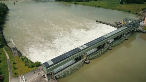 Hydroelectric dam with flowing water through open gates, aerial view from drone