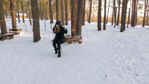Woman Enjoying a Wooden Swing in Snowy Forest
