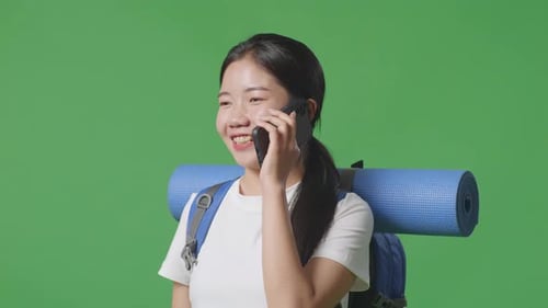 Close Up Of Asian Female Hiker Talking On Smartphone While Standing On Green Screen