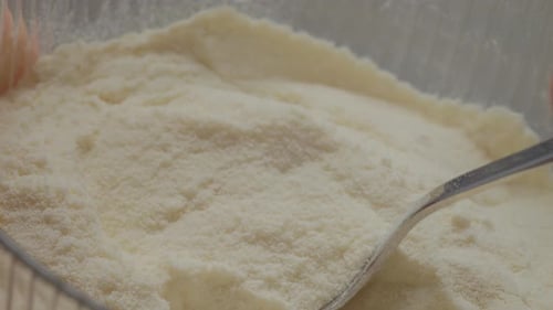 Close-up of spoon filling with powdered milk for smooth mixing