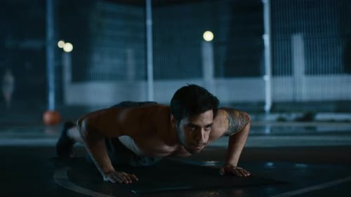 Fit man doing pushups on outdoor basketball court