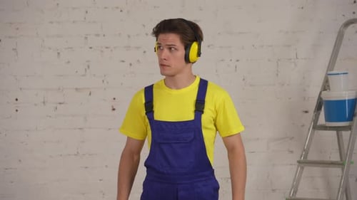 Young Man in Overalls Showing Approval Indoors