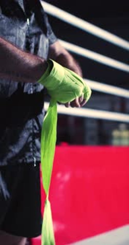 Closeup Slow Motion Footage Captures a Male Fighter Meticulously Wrapping Green Hand Bandages