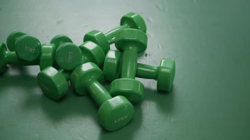 Light Green Hand Weights on Floor in Gym Closeup