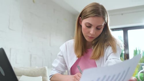 Focused Woman Sits at Home on the Desk and Works Using a Laptop Overworked Manager on a Remote Work