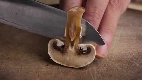 Cutting a Mushroom on a Wooden Cutting Board