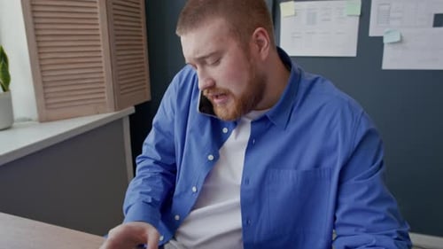 Male UX Designer Phone Calling while Using Computer at Office Desk