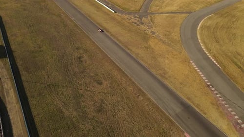 Sports car running on racing circuit of Buenos Aires, Argentina. Slow motion aerial.