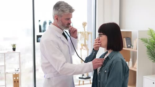 Doctor Listens to Young Woman's Heart with Stethoscope