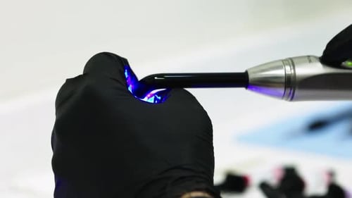 Gros plan d'un dentiste utilisant la lumière ultraviolette pour coller un prototype