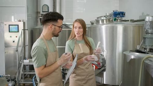 Homme et femme travaillant dans une brasserie artisanale vérifiant le pH de la bière.