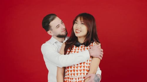 Happy Couple Embracing in Front of Red Backdrop