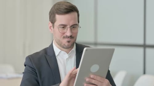 Man Celebrating Success Using Tablet in Office